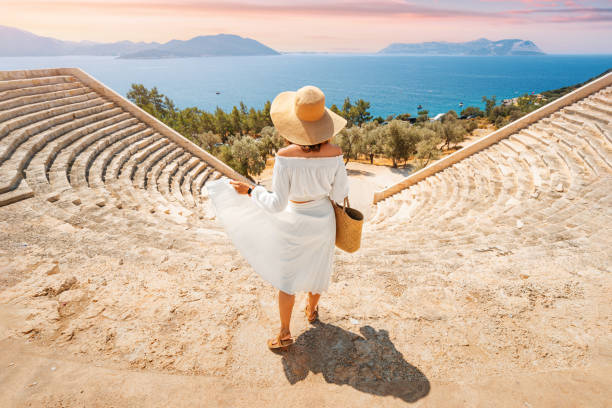 charming and gorgeous woman in white dress and hat explores ancient landmark and ruins of