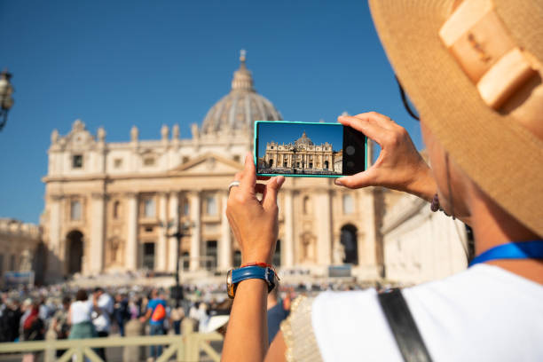 women takes a photo with a smartphone of the st peters basilica in vatican city rome ital