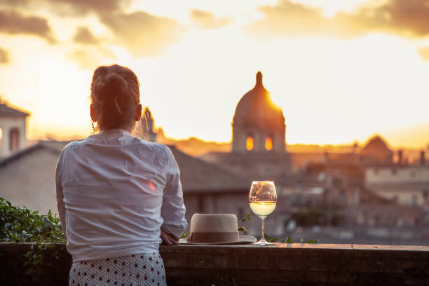 young woman tourist fashion white dress with glass of white wine in front of panoramic vi